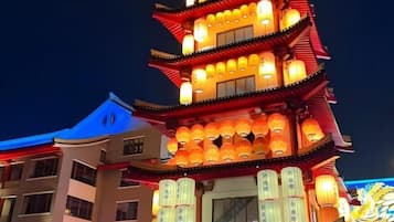 A multi-tiered building with illuminated lanterns, a traditional architectural style, and a sign with Chinese characters.