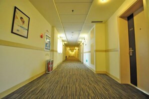 A hotel corridor with a carpeted floor, framed pictures on the walls, and doors on the right. - Jinjiang Inn (LinyiWanxianghui Railway Station Hotel) (Linyi)