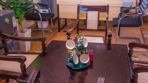 Un comedor con una mesa de madera oscura, rodeada por cuatro sillas con asientos acolchados. Sobre la mesa, un soporte de metal decorativo con platos y una taza.