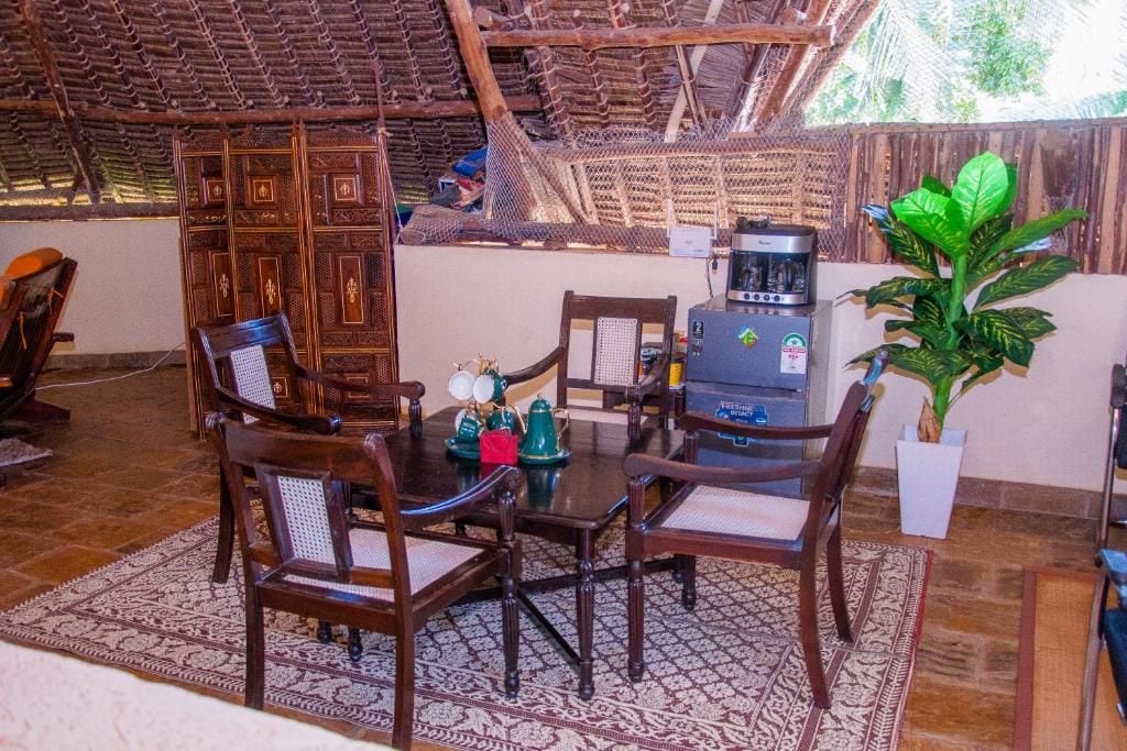 A dining area with a round table, wooden chairs, a coffee machine, and a potted plant.