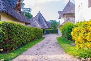 Un sendero conduce a casas tradicionales con techo de paja, rodeadas de exuberante vegetación.