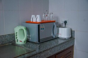 Een keuken met een magnetron, broodrooster en een groen toilet.