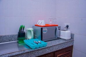 Een keuken met een magnetron, broodrooster en een dienblad met bestek.