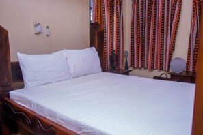 Una cama bien hecha con ropa blanca en una habitación con cabecera de madera.