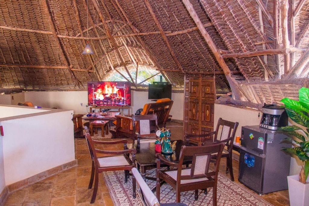 Una habitación con techo de paja, muebles de madera, televisor y refrigerador.