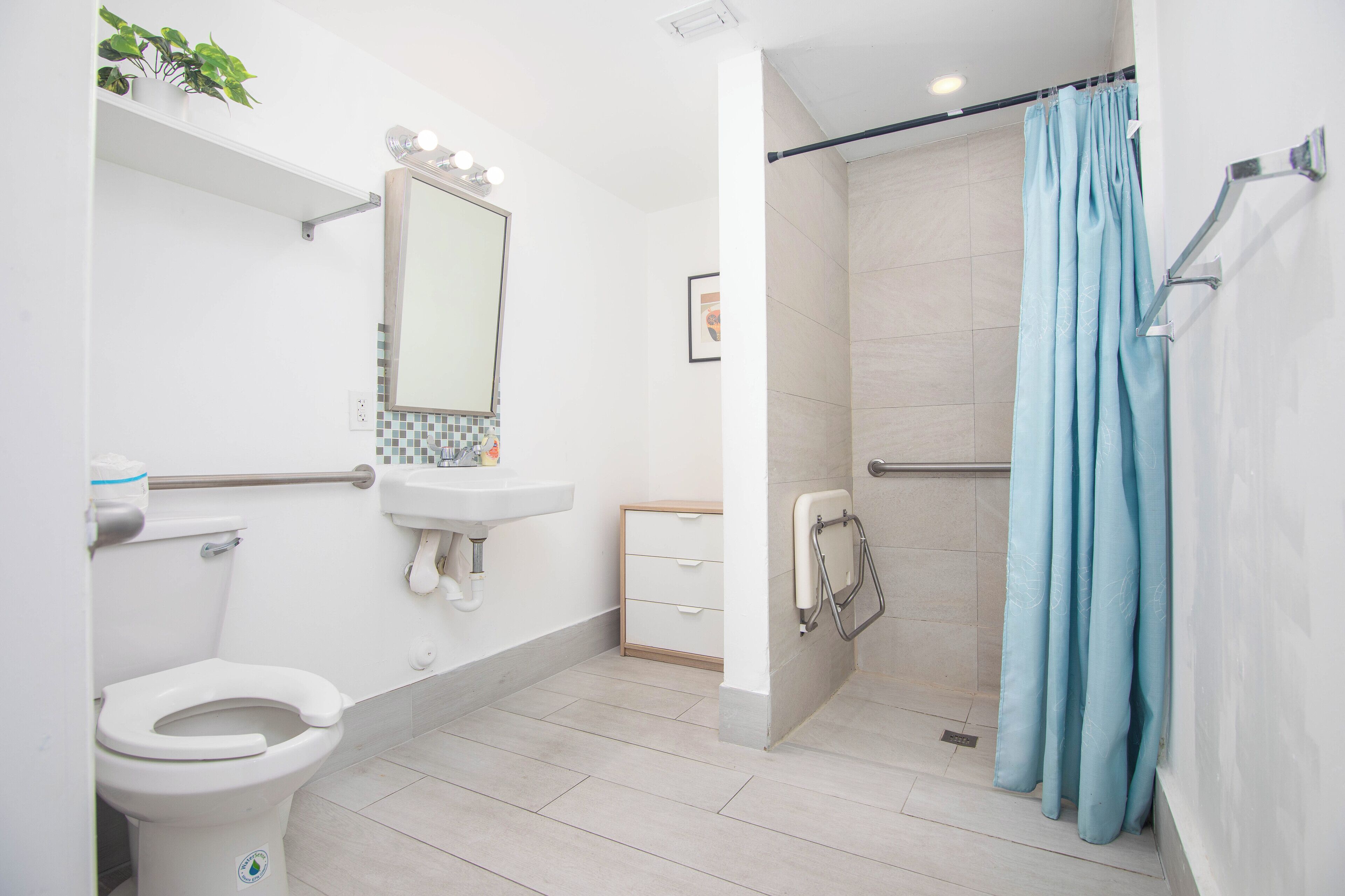 A modern bathroom with a toilet, sink, mirror, and shower area.