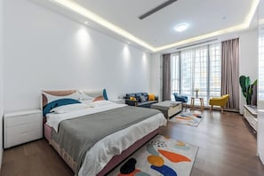 A modern bedroom with a large bed, a sofa, a small table, and a chair. - Zhuhai Hengqin Yuyue Apartment (Zhuhai)
