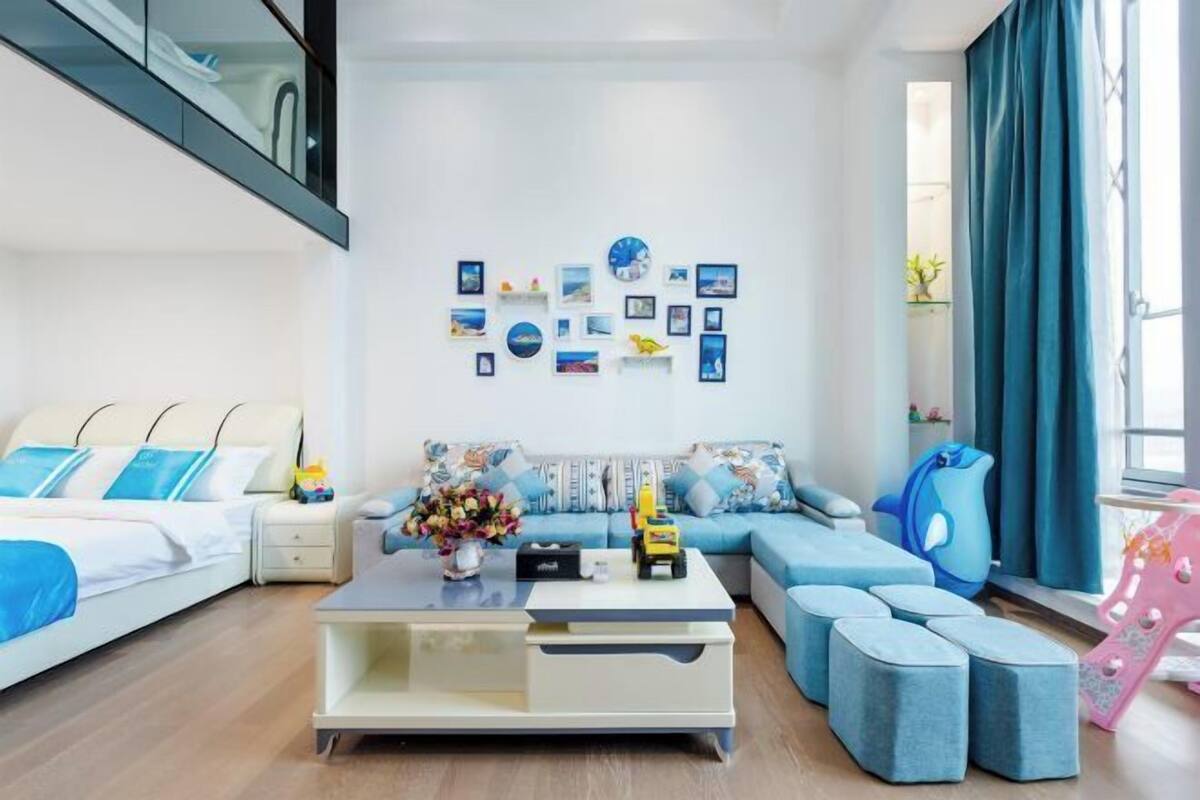 A modern living room with a sofa, ottomans, a coffee table, and a wall decorated with framed pictures.