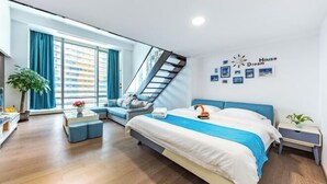 Una camera da letto moderna con un letto, una scala, un divano e una parete con quadri e un orologio.