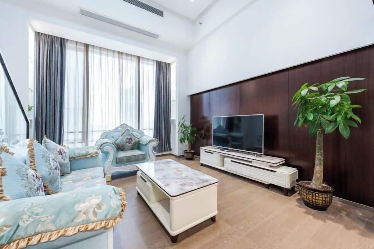A living room with a sofa, a coffee table, a TV, and a potted plant.