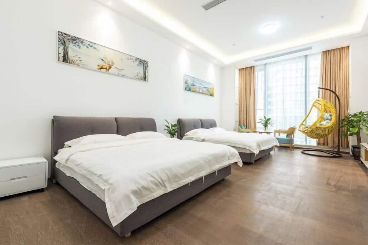 A hotel room with two beds, a hanging chair, and artwork on the walls.