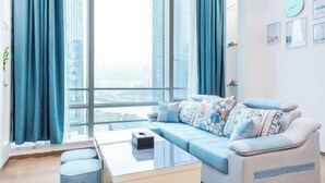 Un soggiorno moderno con divano, tavolino e vista su alti edifici attraverso ampie finestre.