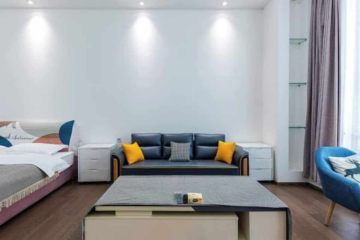 A modern bedroom with a bed, a sofa, a coffee table, and a chair.