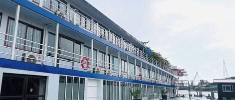 A multi-story hotel with large windows, a blue and white facade, and lifebuoys on the balconies.