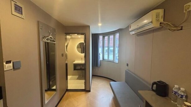 Een moderne hotelkamer met een golvend ontwerp, een ingebouwde bank, een tafeltje met koffiezetapparaat en een raam dat voor natuurlijk licht zorgt.
