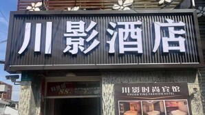 Een hotelschild met Chinese karakters en een kleiner bord met Engelse tekst eronder.