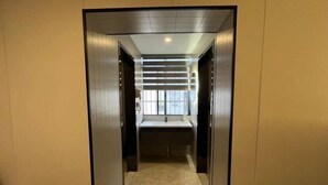 Een modern liftput met een minimalistisch ontwerp, met een lichtgekleurde vloer en wanden, en een centrale lamp.