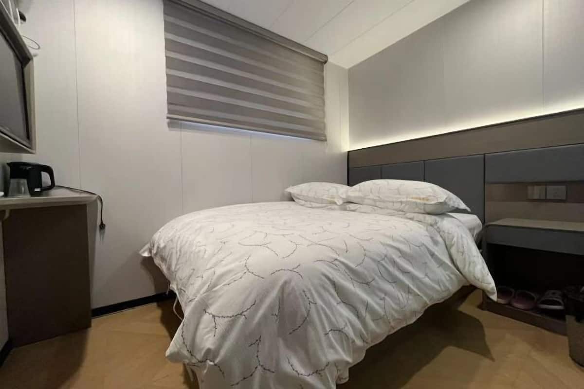 A modern hotel room with a bed, bedside table, and a built-in shelf.