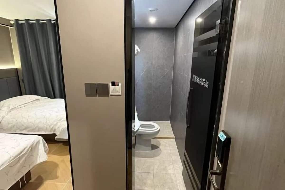 A hotel room with a bed, a toilet, and a shower area.