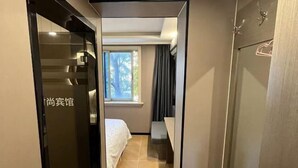 Een hotelkamer met een bed, een raam met gordijnen en een deur met een bordje.