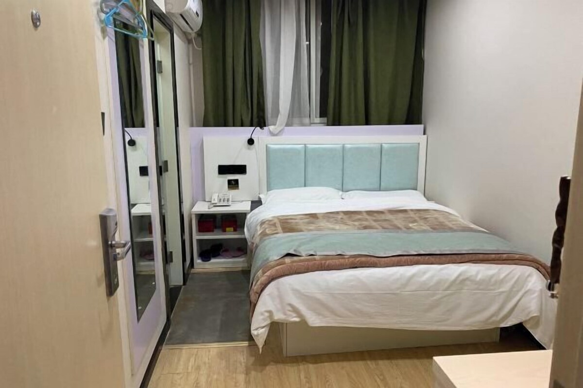 A hotel room with a bed, bedside table, and a wardrobe with a mirror.