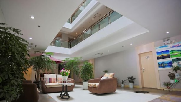 A spacious lobby with a high ceiling, multiple seating areas, and indoor plants. - Motel Lijiang Xueshan Road (Lijiang)