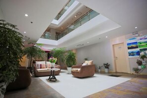 A spacious lobby with a high ceiling, multiple seating areas, and indoor plants. - Motel Lijiang Xueshan Road (Lijiang)