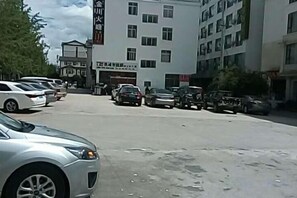 A parking lot with several cars and a building with multiple floors and windows.