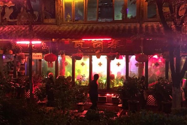 A traditional building with a signboard, illuminated windows, and a person standing in front.
