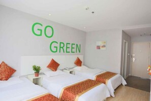A hotel room with two beds, a wall-mounted sign saying 'GO GREEN', and a door leading to another room.