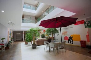 A spacious indoor area with a high ceiling, multiple levels, and a central seating area with a red umbrella.