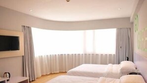 A hotel room with two beds, a TV on the wall, and a window with curtains. - Motel Lijiang Xueshan Road (Lijiang)