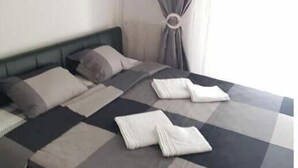 Ett hotellrum med en säng, kuddar, ett täcke och ett fönster med gardiner.