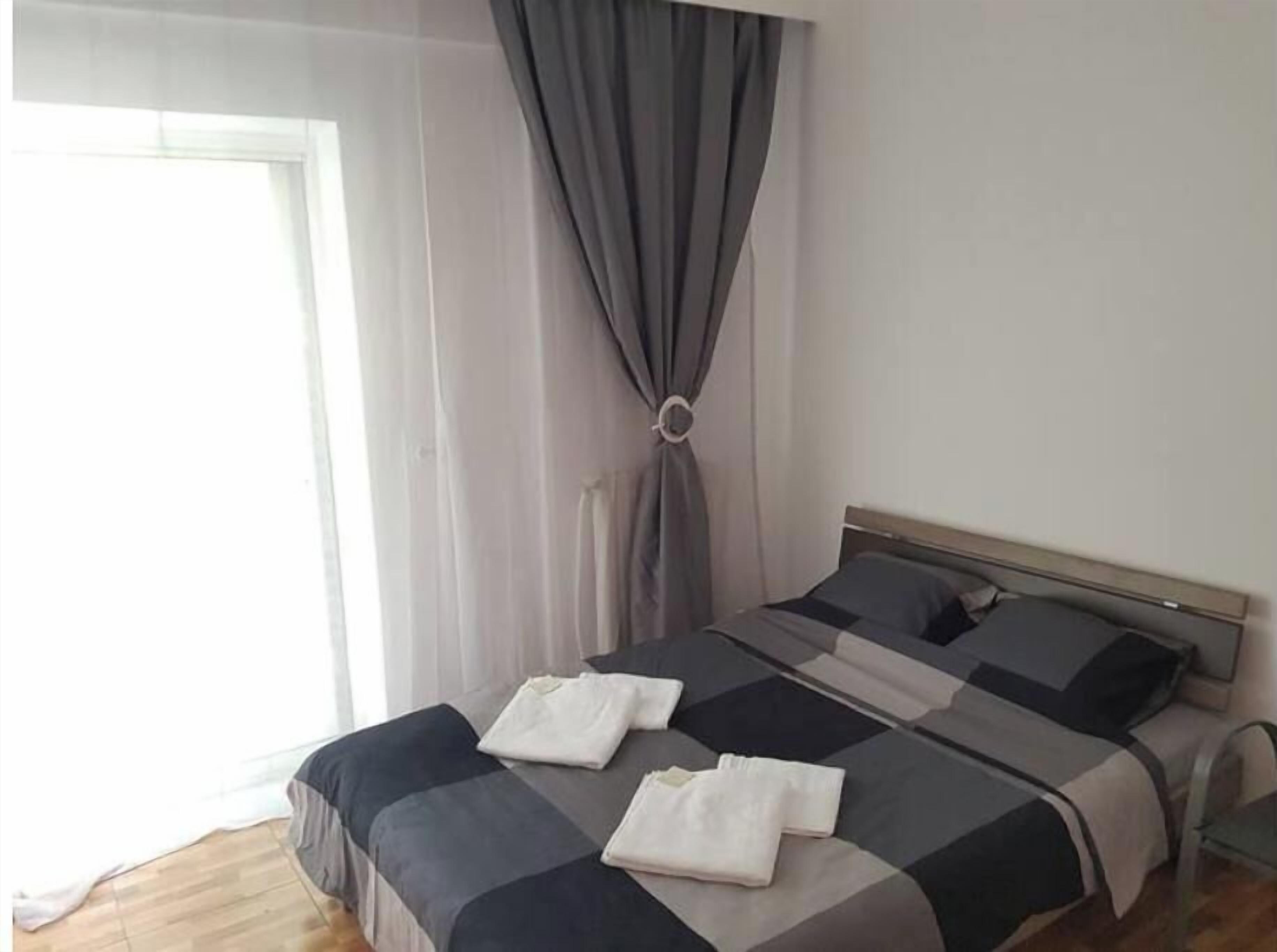 A neatly made bed with a grey and white striped bedspread, two pillows, and folded white towels.