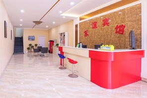 A reception area with a red counter, a TV, and a staircase in the background. - Zhengding Friendship Express Hotel (Zhengding)