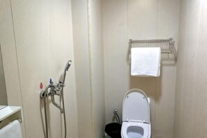 Un baño pequeño con inodoro, ducha y toallero.