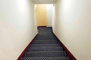 Un estrecho pasillo con alfombra estampada que lleva a una puerta al final.