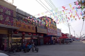 Calle con diversas tiendas, incluyendo un restaurante y una tienda con toldo rojo.
