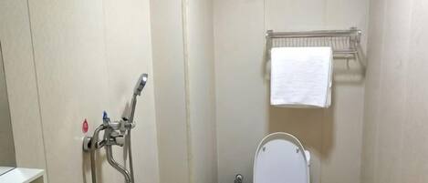 Un baño pequeño con inodoro, ducha y un perchero para toallas.