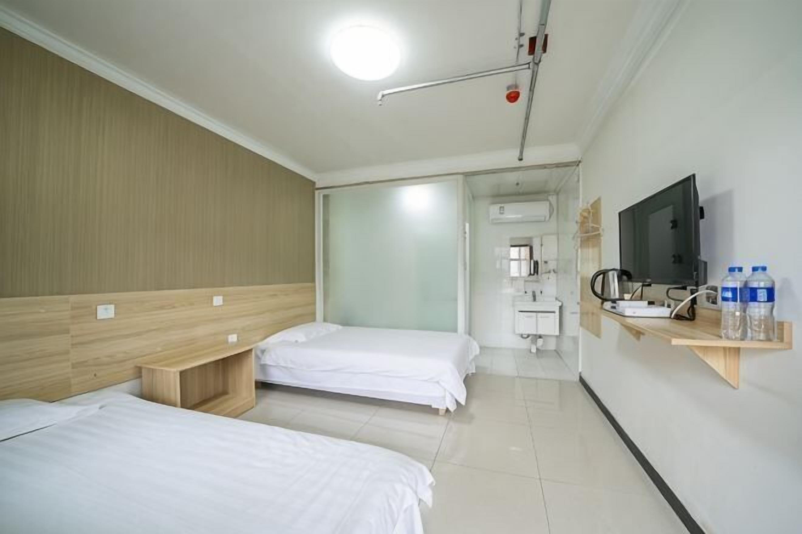 Una habitación de hotel con dos camas, televisión, lavamanos y espejo.