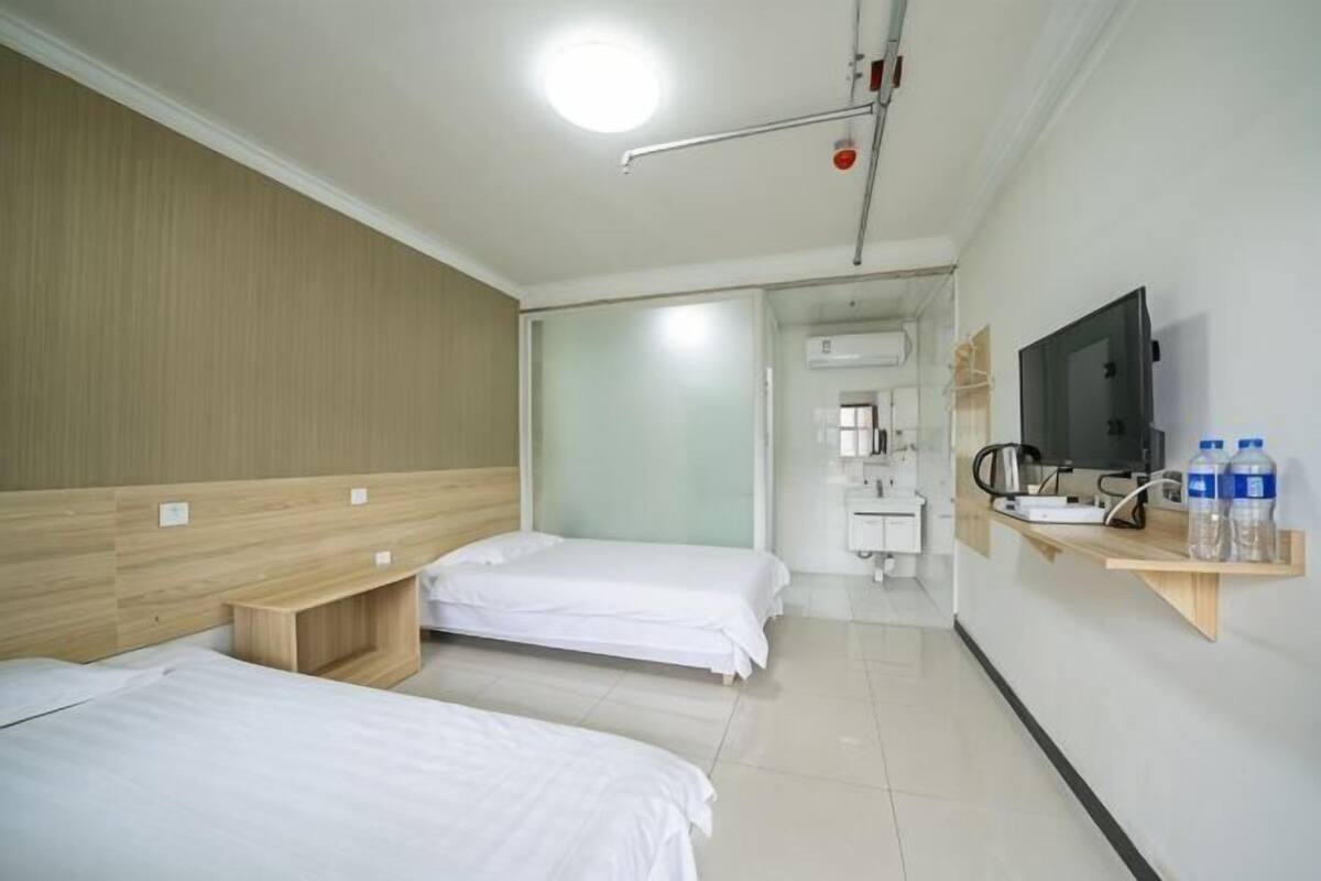 Een hotelkamer met twee bedden, een televisie, een wastafel en een spiegel.
