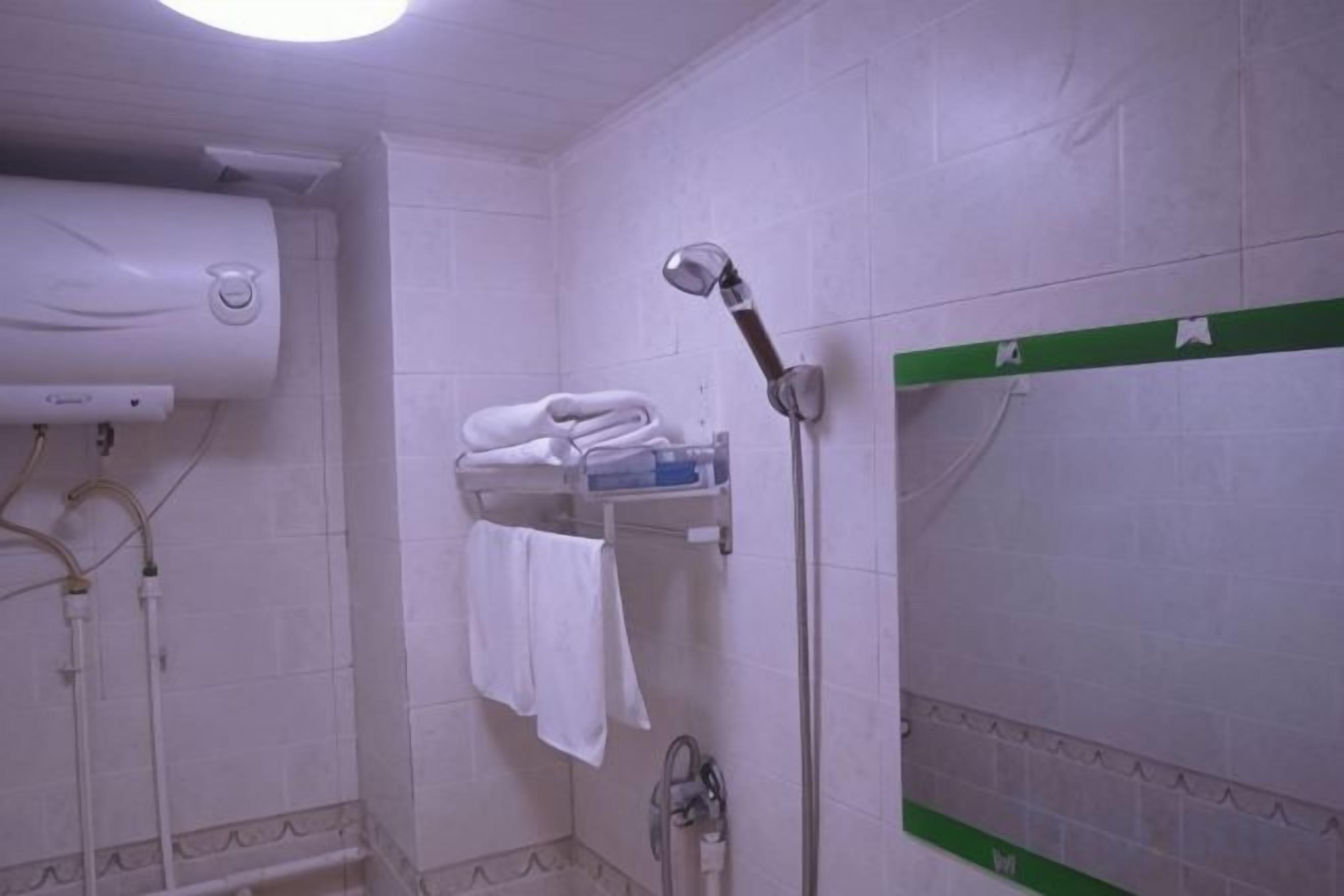 A bathroom with a towel rack, a shower, and a wall-mounted heater.