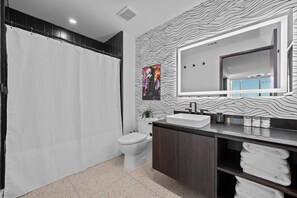Ein modernes Badezimmer mit Duschvorhang, Toilette, Waschbecken mit Spiegel und Handtuchhalter.