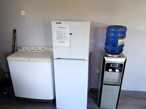 A white washing machine, a white refrigerator with a house rules notice, and a water dispenser. - Cozy Private Oasis in Lusaka w/Pool, AC, Starlink High-speed Wi-Fi +Pet-Friendly (Lusaka)
