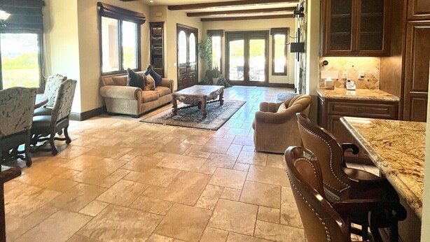 A spacious living area with a large dining table, comfortable seating, and a view of the outdoors. - Luxury Home on Secluded Ranch, near beaches and hiking (San Diego)