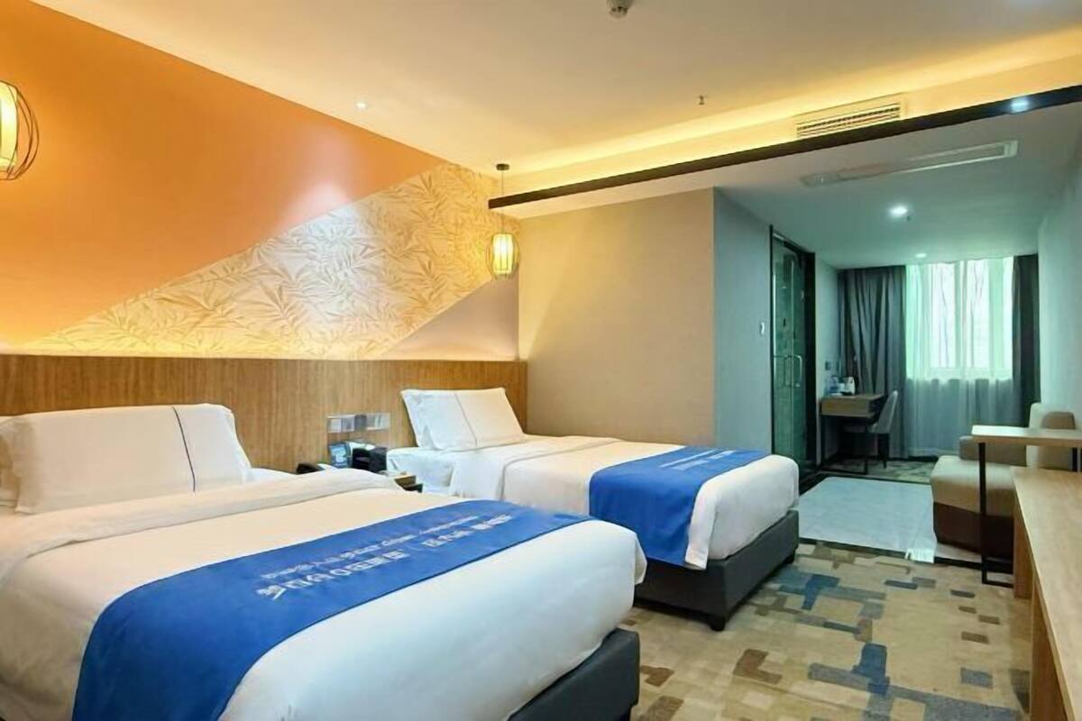 Una habitació d'hotel amb dos llits, un escriptori i vista a la ciutat.