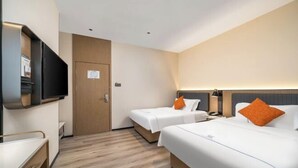 Una camera d'albergo con due letti, una TV, una scrivania e una porta.
