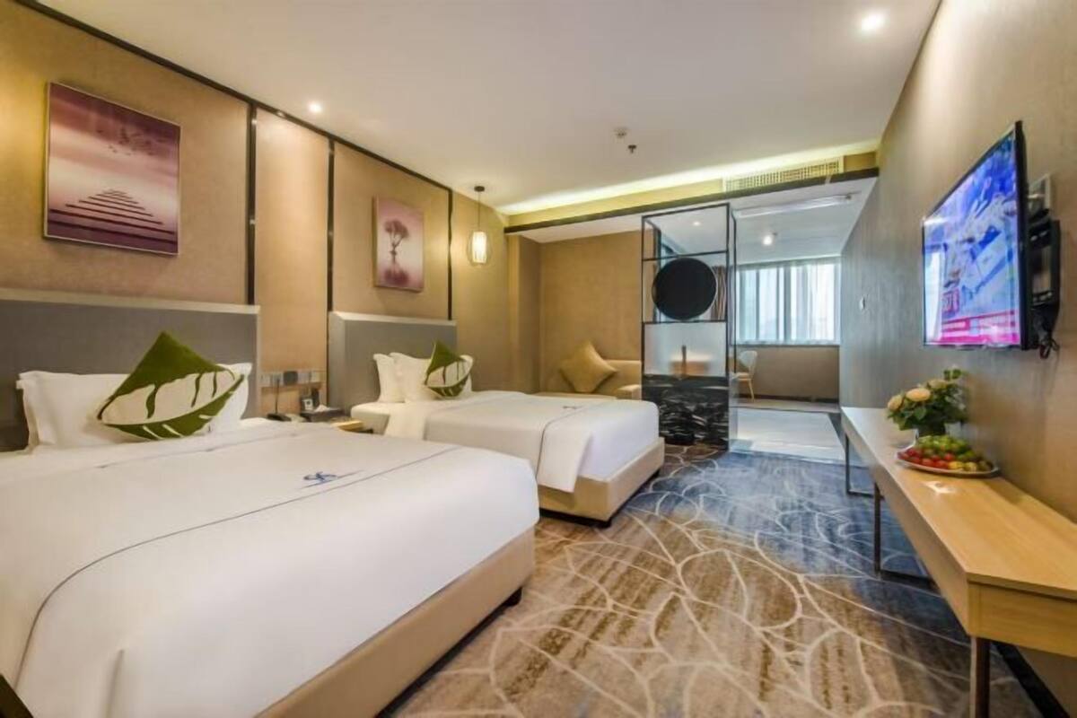 Habitació d'hotel amb dos llits, un escriptori, una televisió i vistes a la ciutat.