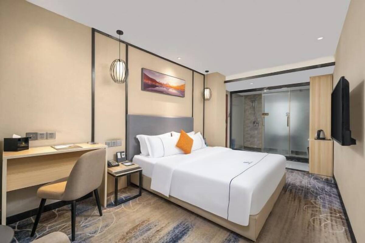 Habitació d'hotel amb llit, escriptori, cadira i televisió.
