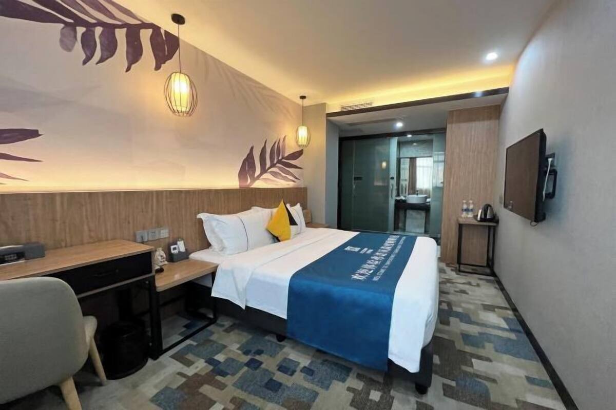 Una habitació d'hotel amb llit, escriptori, cadira i televisió penjada a la paret.
